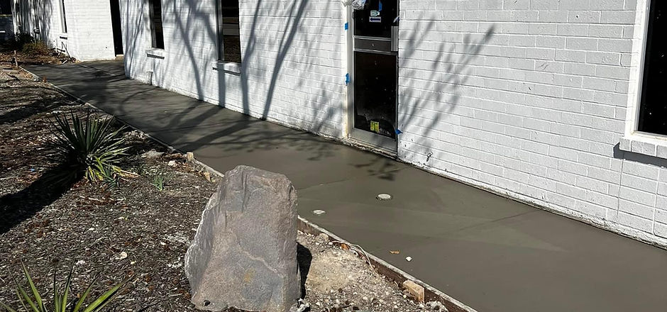 Fresh concrete entry walkway beside a white brick home