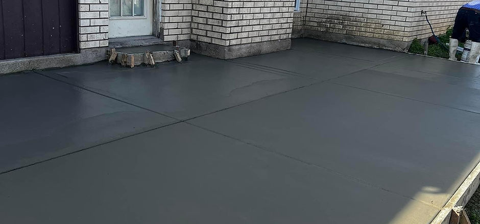 Completed dark concrete slab beside a brick home
